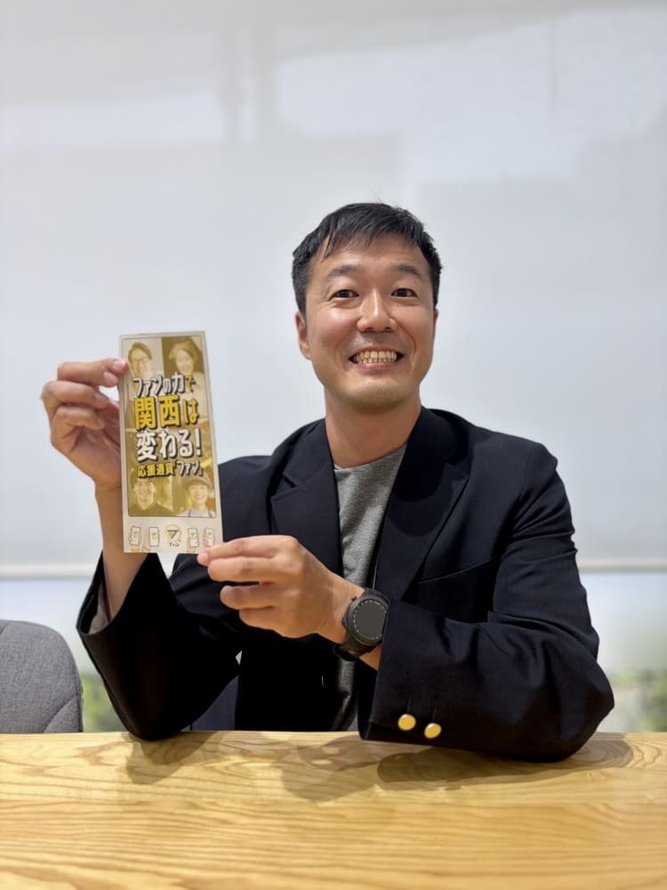 ファンのリーフレットを持つ小西社長